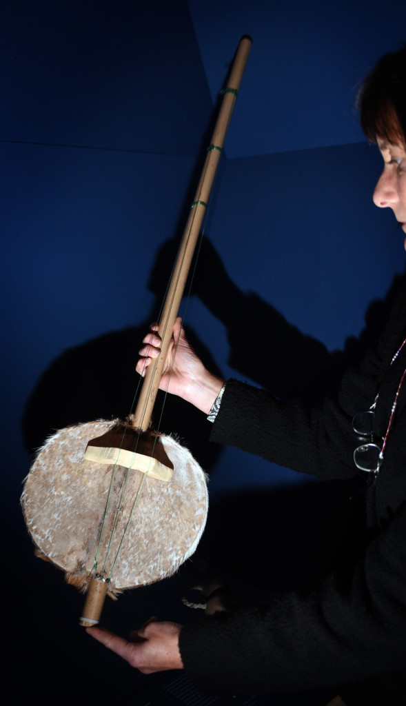 JANET TOPP FARGION WITH THE AKONTING INSTRUMENT ON DISPLAY IN THE BRITISH LIBRARY'S WEST AFRICA EXHIBITION. PHOTO BY CLARE KENDALL FOR THE BRITISH LIBRARY.